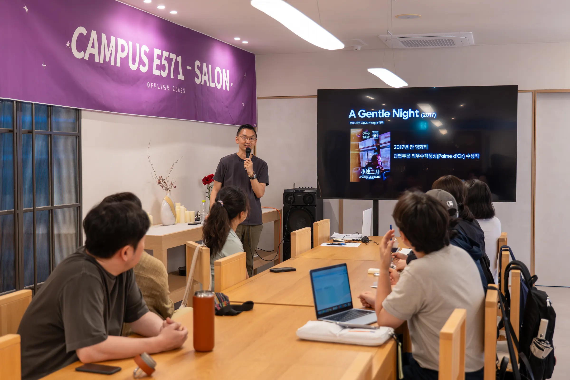 CAMPUS E571 SALON 현수막과 스크린 앞에서 진행 중인 시네마 토크