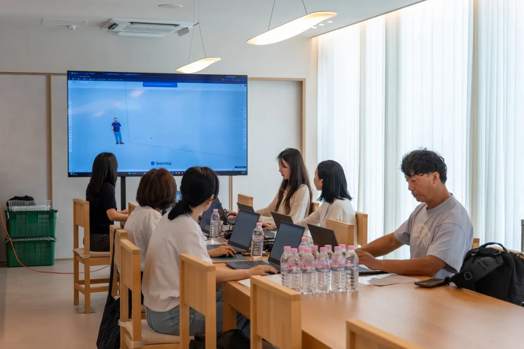 스크린에 띄운 3D 렌더링 이미지와 노트북 앞의 참가자들.